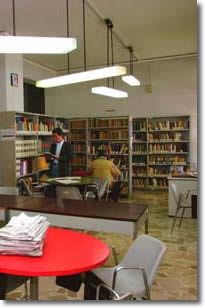 ampio salone con librerie, sedie, scrivanie e persone che leggono